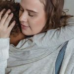 Adult holding a child in a comforting embrace