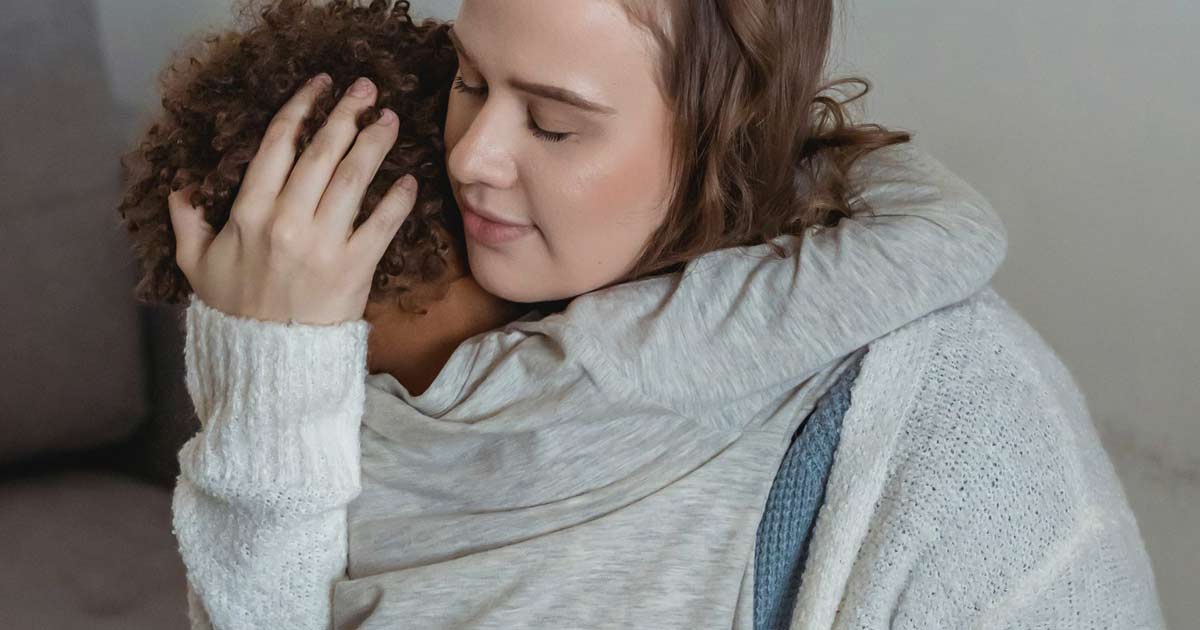Adult holding a child in a comforting embrace