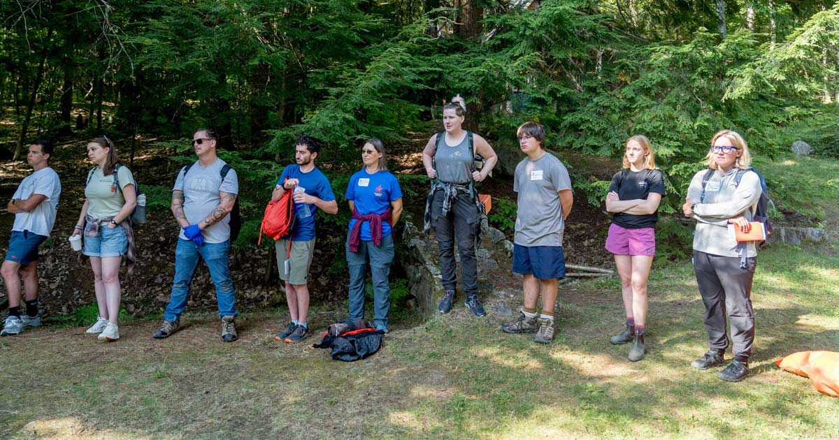 Group of camp staff members standing together in a forest clearing during an outdoor training session
