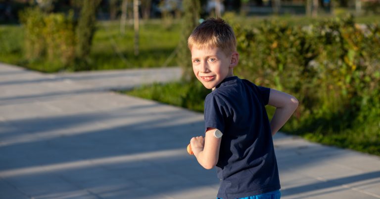 Child wearing a continuous glucose monitor outdoors at summer camp